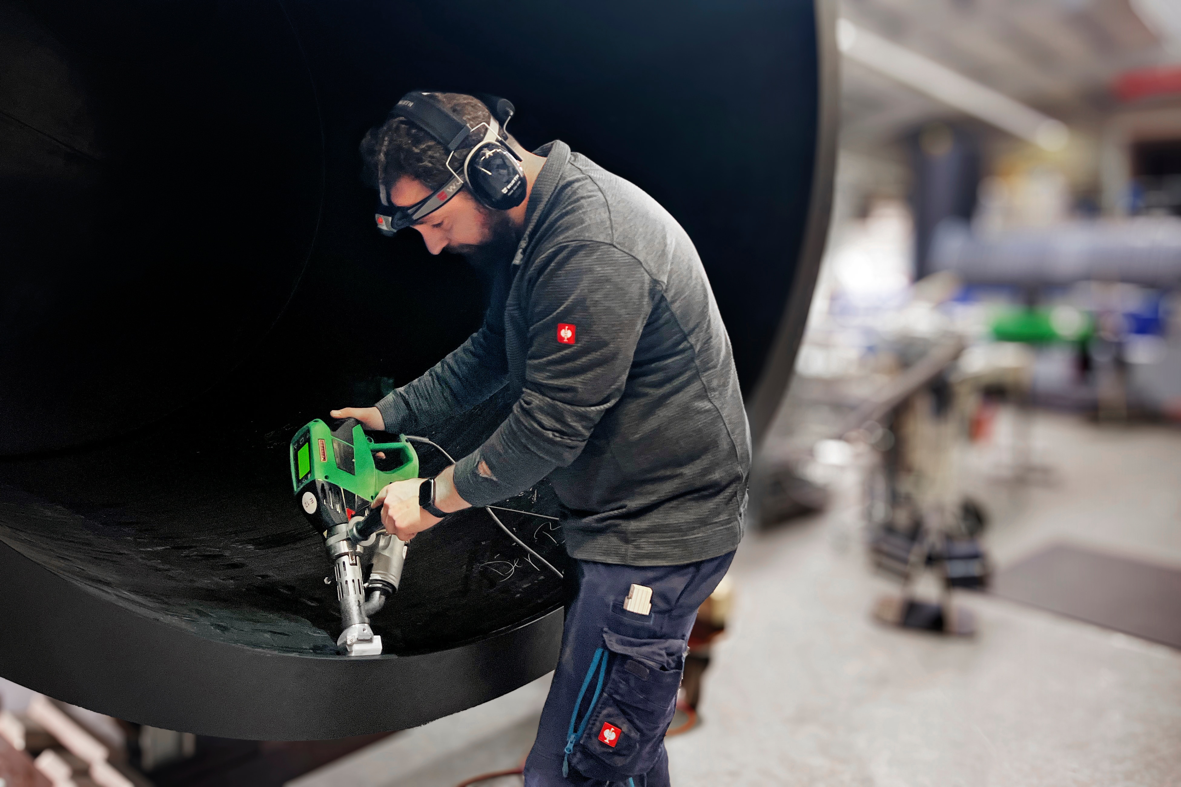 A person using a WELDPLAST extruder from Leister in a factory to weld a PE pipe.